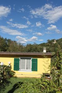 a yellow house with green shutters in a yard at B&B Ca dei Fre in Genoa