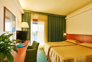 Habitación de hotel con cama, escritorio y TV. en Hotel Rialto, en Grado