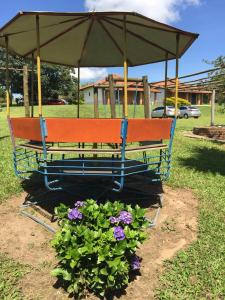 um banco de parque com um guarda-chuva sobre algumas flores em Chales da Serra em São Pedro