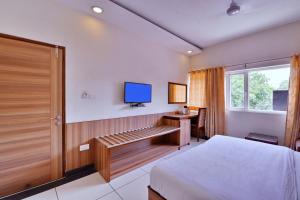 a bedroom with a bed and a tv on the wall at Hotel Aricent in Chandīgarh
