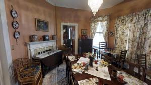 Hanna House Bed & Breakfast في نيو برن: غرفة معيشة مع طاولة وكراسي ومدفأة