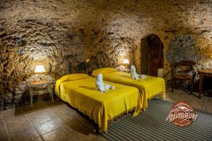 a bedroom with two beds in a stone room at Casa Cueva El Mimo in Artenara