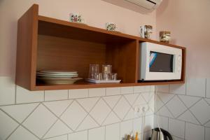 a kitchen with a microwave and plates in a cabinet at Magdaléna Vendégház in Hajdúszoboszló