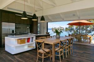 una cocina abierta con mesa de madera y sillas en The Point Luxury Villa en Taupo
