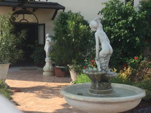 Una statua di una donna in piedi in una fontana di Casa Nives a San Pietro in Casale