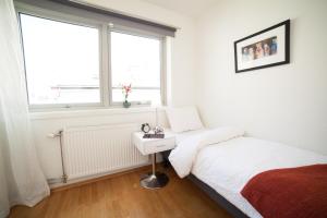 a white bedroom with a bed and a window at BJØRVIKA APARTMENTS, Teaterplassen, Oslo city center in Oslo