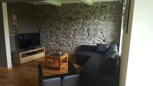 a living room with a couch and a stone wall at Gite Dardenne in Bertrix