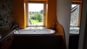 un bagno con ampia vasca e finestra di Gite Dardenne a Bertrix