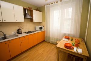 モスクワにあるApartment on Yartsevskayaのキッチン(オレンジ色のキャビネット、木製テーブル付)