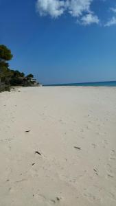 una spiaggia con impronte di piedi nella sabbia e nell'oceano di Mare a SantaMargherita a Pula