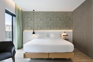 バルセロナにあるニウ バルセロナ ホテルのベッドルーム(大きな白いベッド1台、椅子付)