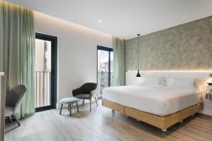 a bedroom with a large white bed and two chairs at Niu Barcelona Hotel in Barcelona