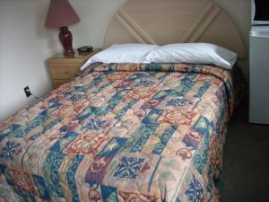 a bed with a colorful quilt on it in a room at Motel le Verseau in Sorel