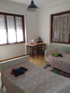 a bedroom with two beds and a table and windows at Ristoro 25 Aprile in Tolmezzo