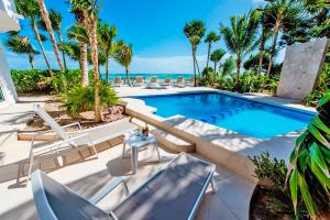 una piscina con sillas, una mesa y el océano en Villa Mar Azul Luxury Villa en Tulum