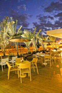 a deck with tables and chairs and umbrellas at Vitória Hotel Convention Paulínia in Paulínia