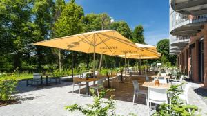 a patio with tables and chairs with umbrellas at Steverbett Hotel in Lüdinghausen