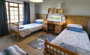 a bedroom with two beds and a desk with a dresser at Renovated Fishermans Cottage in Hermanus