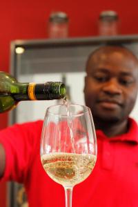 a man pouring white wine into a wine glass at The One 8 Hotel - Solar Power located in Green Point in Cape Town