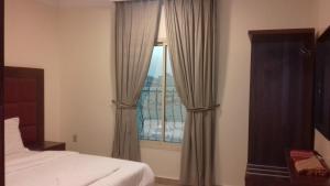 Un dormitorio con una ventana con cortinas y una cama en Danar Hotel Apartments 5 en Al Khobar