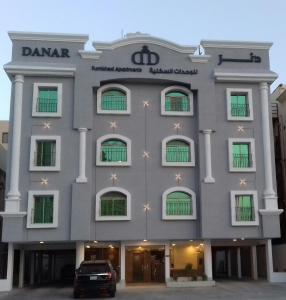 a large gray building with a car parked in front at Danar Hotel Apartments 5 in Al Khobar