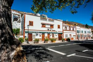 a building on a city street with a tree at Casa Cueva El Molino By Artenatur in Artenara
