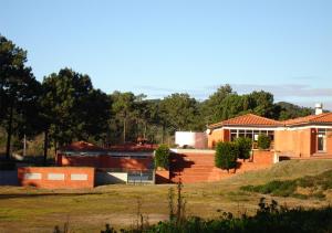 una casa en una colina con árboles en el fondo en Parque de Campismo Orbitur Foz de Arelho. en Foz do Arelho