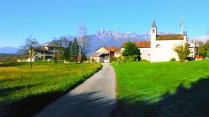 a road leading to a church with a grass field at B&b Col del Vin in Belluno