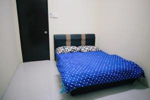 a bed with a blue comforter in a room at Arau Idaman Homestay in Arau