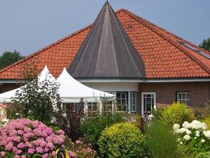 una casa con techo de baldosa naranja con flores en Hotel Am Steendamm en Oyten