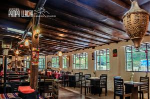 Un restaurante con techos de madera y mesas y sillas. en Hosteria Pampallacta, en Papallacta