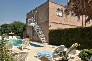 a pool with white chairs and a staircase next to a building at Dormi's - Adult's Only in Mina Clavero