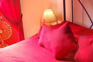 a red bed with red pillows and a lamp at Riad Le Grand Large in Essaouira
