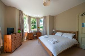 a bedroom with a large white bed and a television at The Old Inn in Mullion