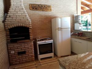 a kitchen with a brick oven and a refrigerator at Chacara Recanto dos Passaros 01 in Olímpia