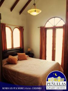 a bedroom with a large bed with two windows at Apart Hotel Penuelas in Coquimbo