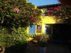 un edificio amarillo con flores y plantas en un patio en Pousada Repouso do Guerreiro, en Búzios