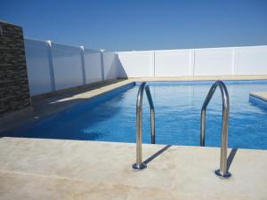 a swimming pool with blue water and metal hand rails at Appart Hotel Star in Tangier