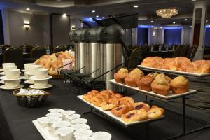 a table with several trays of bread and pastries at Adria Hotel and Conference Center in Queens