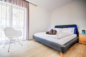 a bedroom with a bed and a chair and a window at Apartamenty Nautica blisko plaży in Niechorze