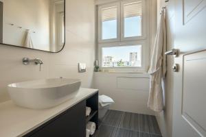 een witte badkamer met een wastafel en een raam bij Magic View Apartments in Zadar