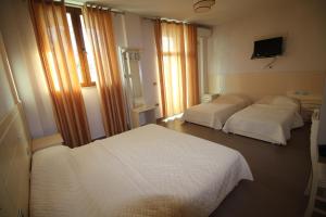 2 camas en una habitación de hotel con sábanas blancas en Hotel Piazza, en Peshkopi