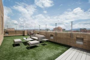 un patio all'ultimo piano con prato, tavolo e sedie di Attik Luxury Apts a Bogotá