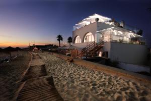 a building on the beach at night with the sun setting at Golden Beach Guest House & Rooftop Bar in Faro