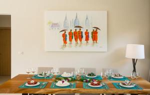 a dining room table with blue napkins and a painting at Villa Desi in Bang Tao Beach