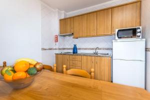 una cucina con tavolo e cesto di frutta di Apartamentos Arcada a Quarteira Altre 11 foto