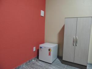 a small refrigerator in a room with a red wall at Pousada Centaurus in Alto Paraíso de Goiás
