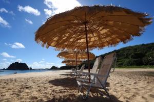 dwa krzesła i parasol na plaży w obiekcie Casa Conceição w mieście Fernando de Noronha