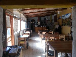 a restaurant with wooden tables and chairs and windows at Rancho Lamaral Hostel & Camping in Rodeo