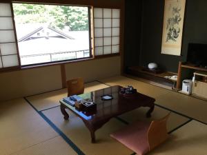 a living room with a table and a window at Yakushi no Yu Yumotokan in Kusatsu